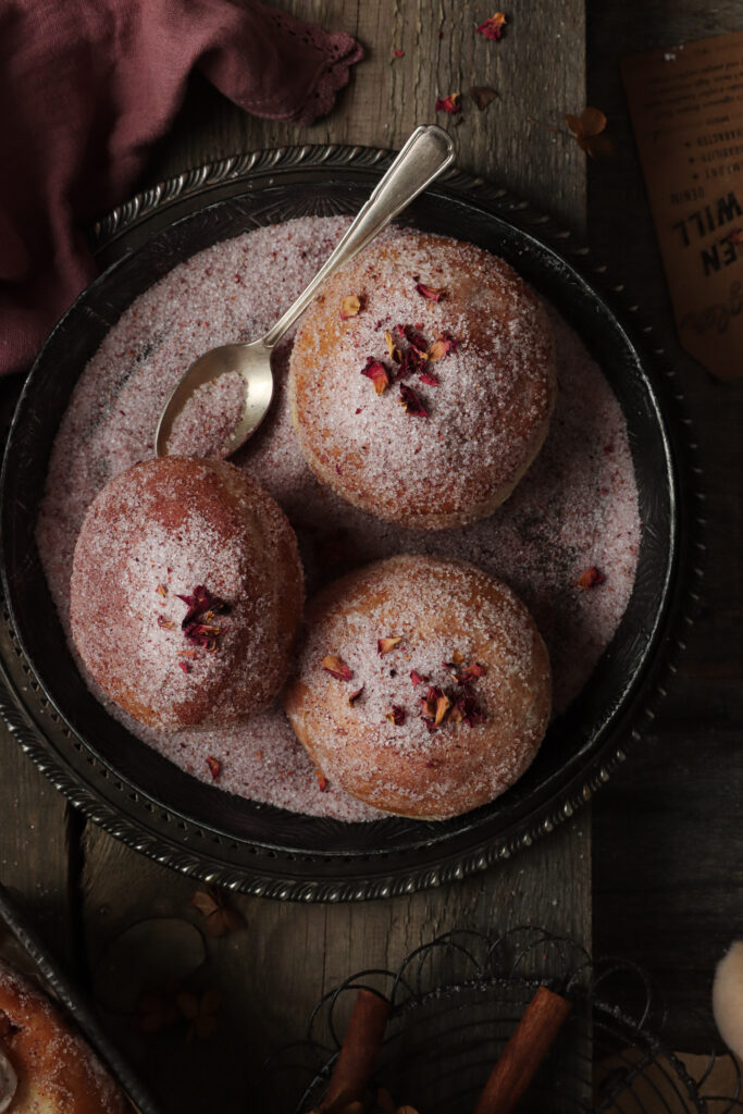 pączki ułożone na rustykalnej tacy lub talerzu posypane cukrem i różą, fotograf kulinarny lublin pyszny kadr kinga ciszewska storytelling a fotografia kulinarna 