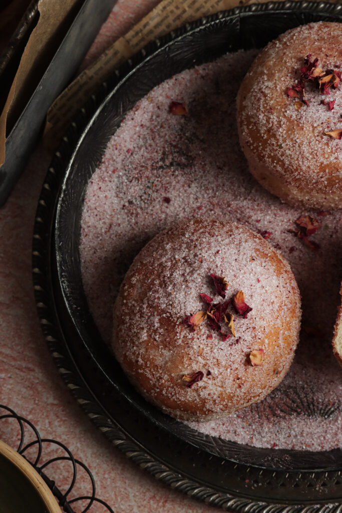 zdjęcie makro pączków z różą, pączki leżą na rustykalnej tacy lub talerzu posypane cukrem pudrem, fotograf kulinarny lublin pyszny kadr kinga ciszewska storytelling a fotografia kulinarna