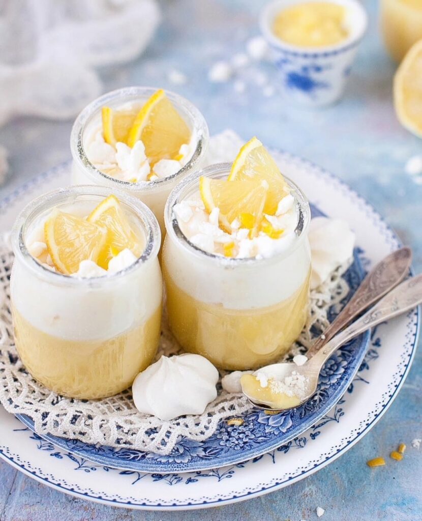 trzy desery z lemon curd i kremem na bazie mascarpone, udekorowane bezami i plasterkami cytryny. lekki wiosenny nastrój