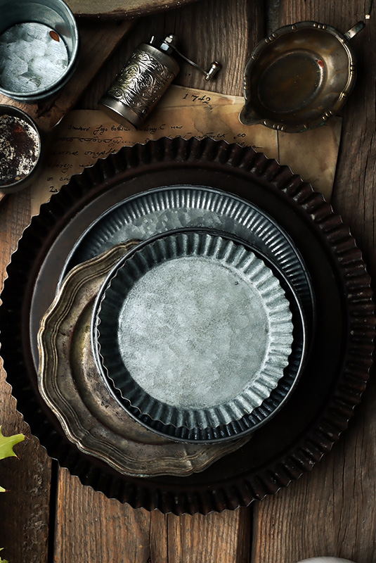 akcesoria do fotografii kulinarnej w stylu dark mood, na zdjęciu widoczne tace, talerze i miski wykonane z metalu