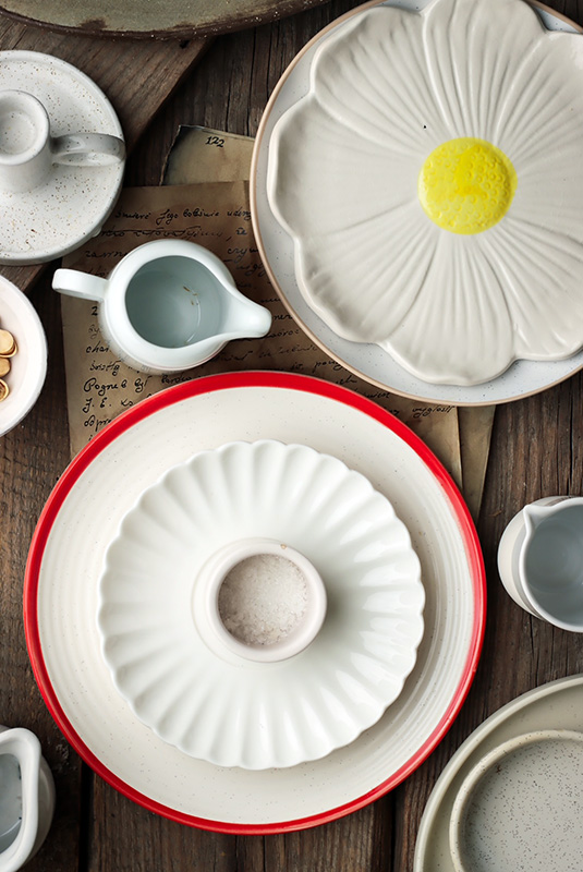 jasne akcesoria do fotografii kulinarnej, na zdjęciu widoczna ceramika - talerze, miski, mleczniki w białym i kremowym kolorze