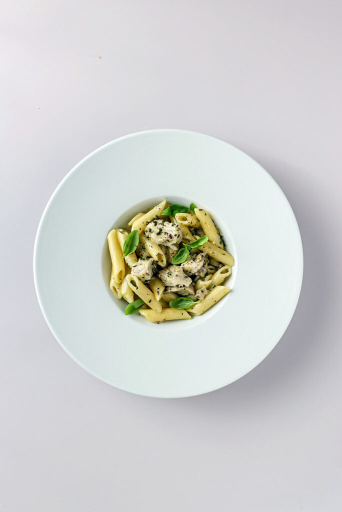 Makaron penne z kurczakiem i bazylią podane w talerzu