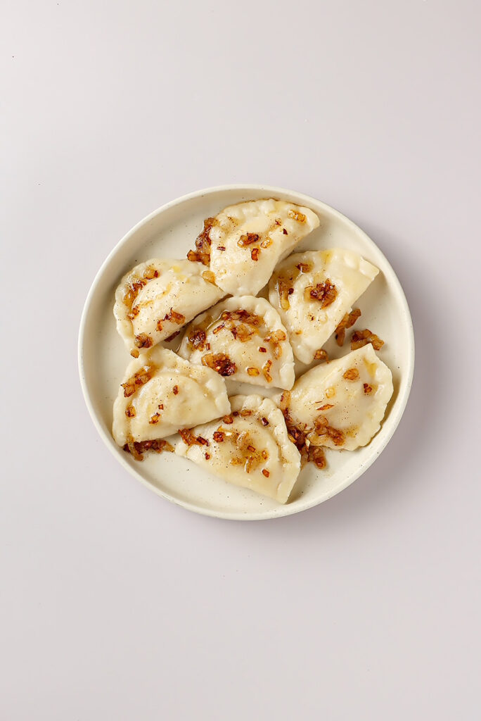 Ruskie pierogi ze skwarkami podane na talerzu. Tak należy pokazywać zdjęcia potraw w aplikacjach do zamawiania jedzenia