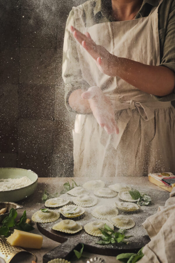 Profesjonalna fotografia kulinarna pokazująca proces przygotowania domowych ravioli. Zdjęcie z kulis sesji, idealne do pokazania atmosfery pracy food stylisty i fotografa.